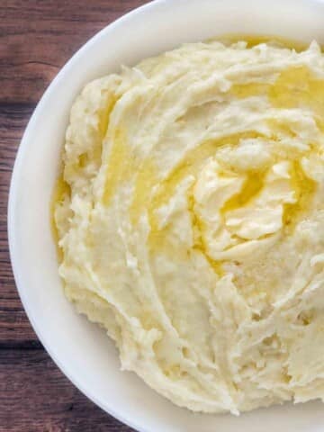 Mashed potatoes with butter melting on top in white bowl.