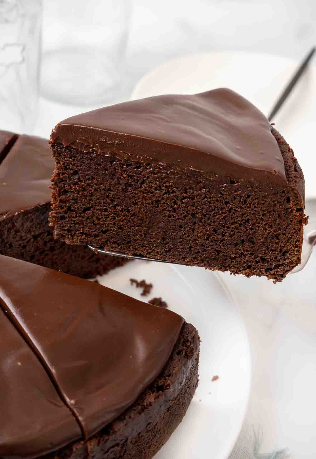 slice of chocolate mud cake being taken out of whole cake.