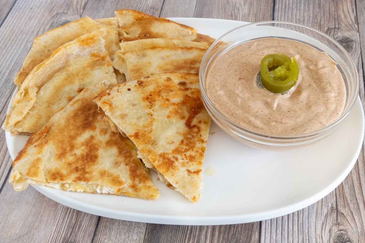 Quesadilla sauce with cut up quesadilla on white platter.