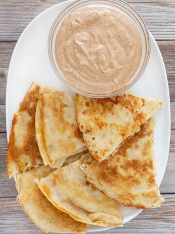 Quesadilla dipping sauce with cut up quesadilla on white platter.