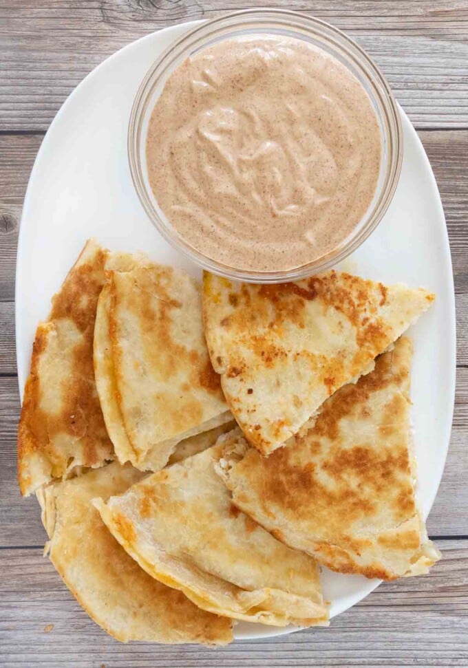 Quesadilla dipping sauce with cut up quesadilla on white platter.