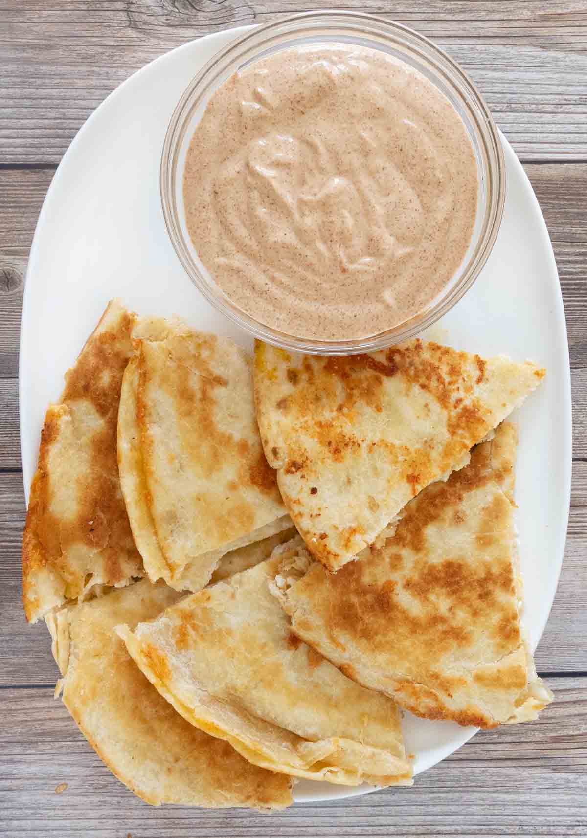 Quesadilla sauce with cut up quesadilla on white platter.