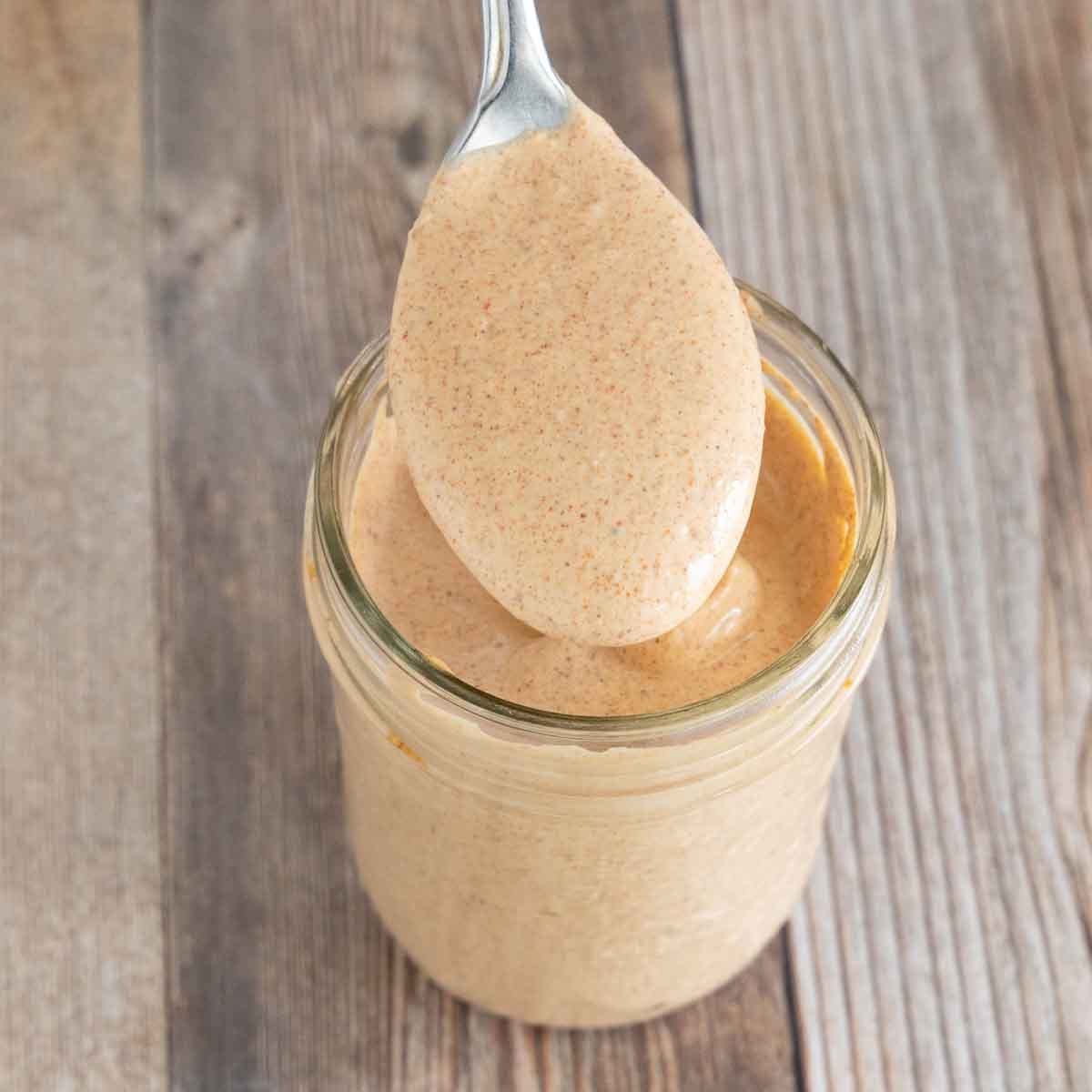 Quesadilla sauce in glass jar with a spoon.