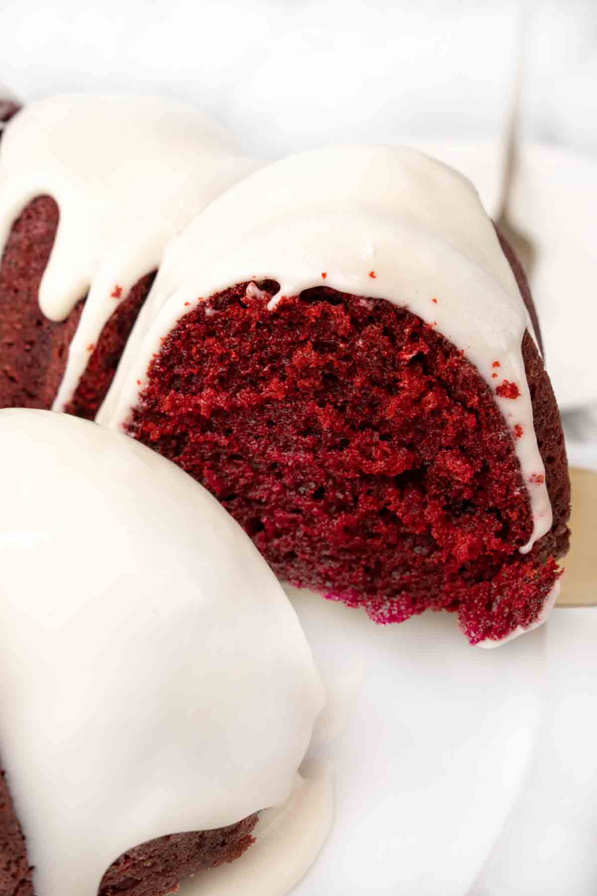 Slice of red velvet cake being taken out of whole cake.
