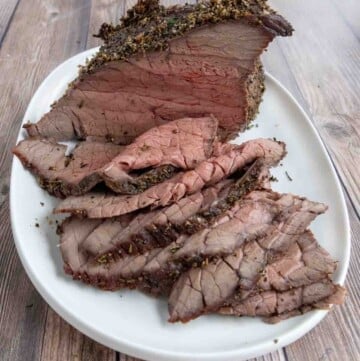 sliced top round roast on a white platter.