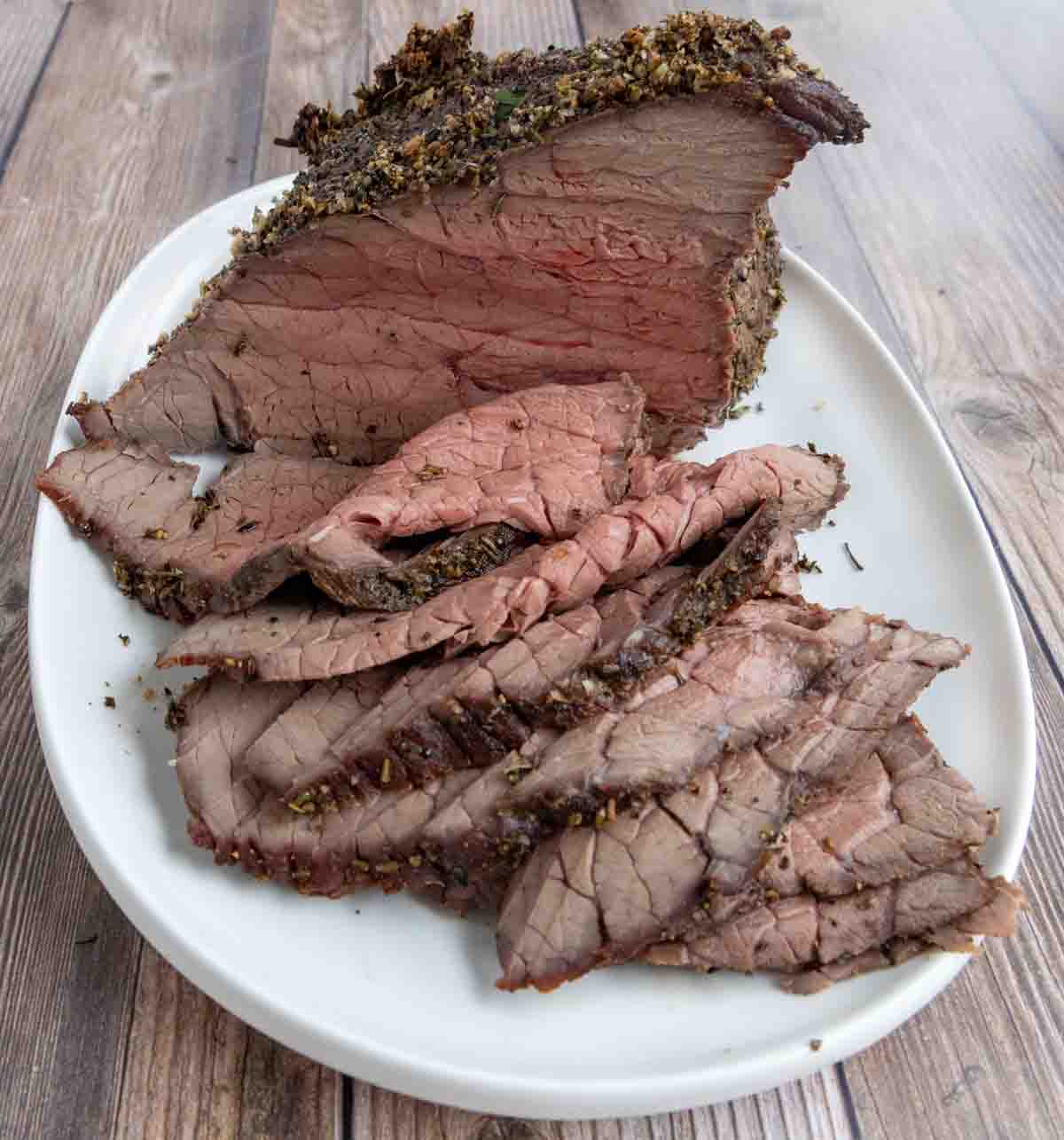 sliced top round roast on a white platter.