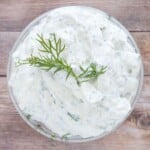 Yogurt dill dip with a sprig of dill on top in a glass bowl.