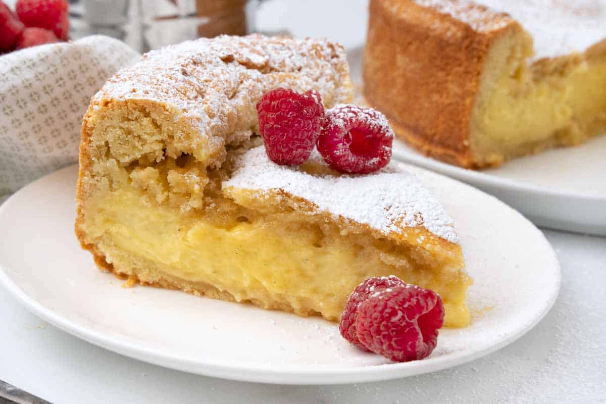 Slice of Gateau Basque with raspberries on a white plate.