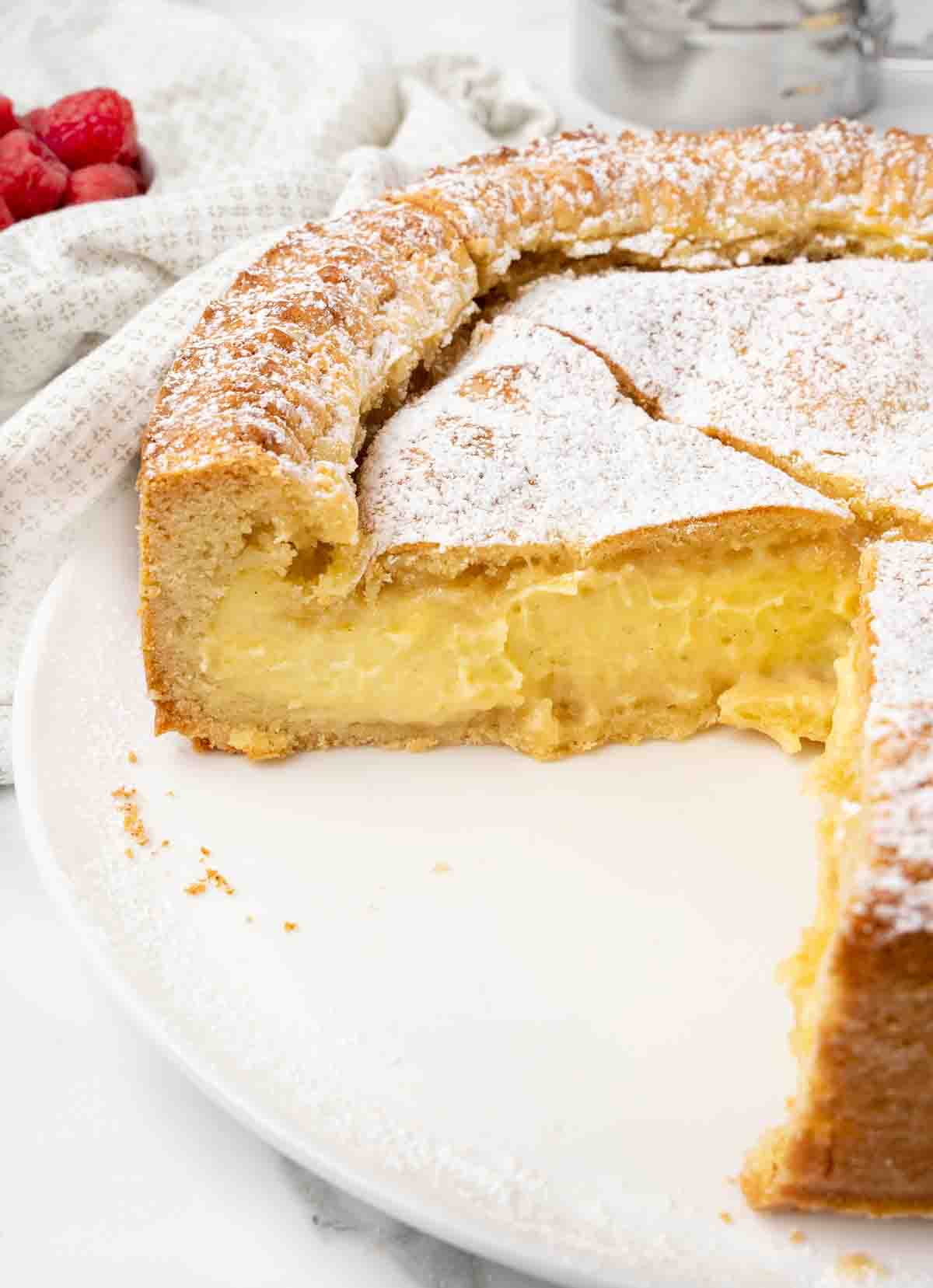 side view of sliced Gateau Basque on a white platter.