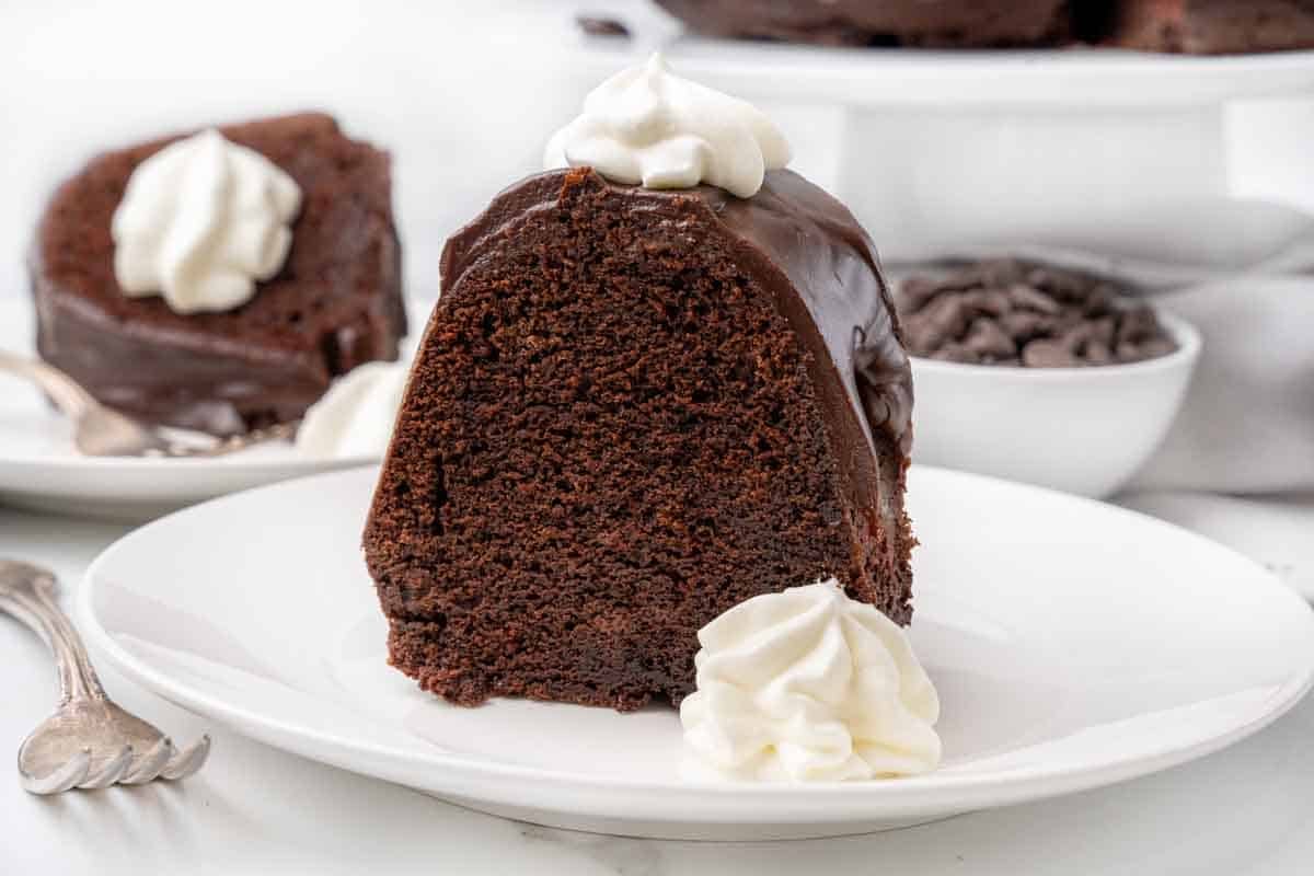 slice of chocolate brownie cake with whipped cream on a white plate.