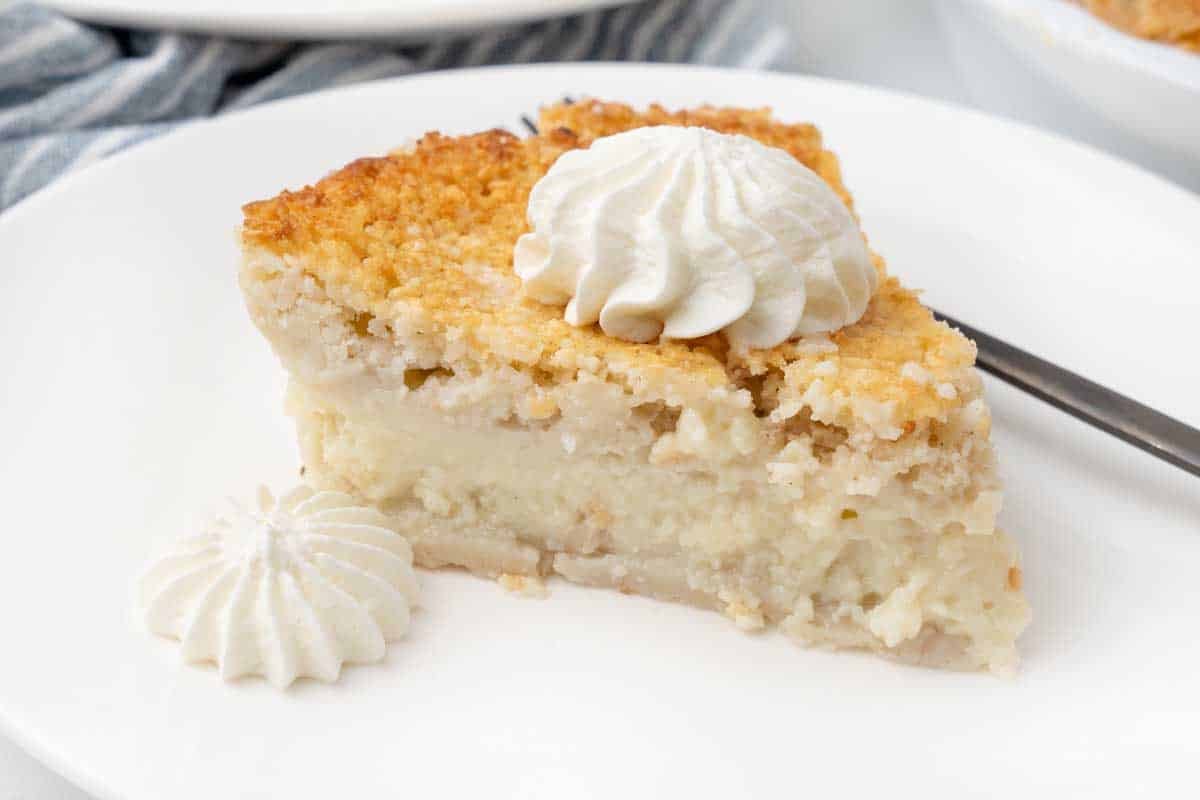 Slice of impossible pie with whipped cream on a white plate.