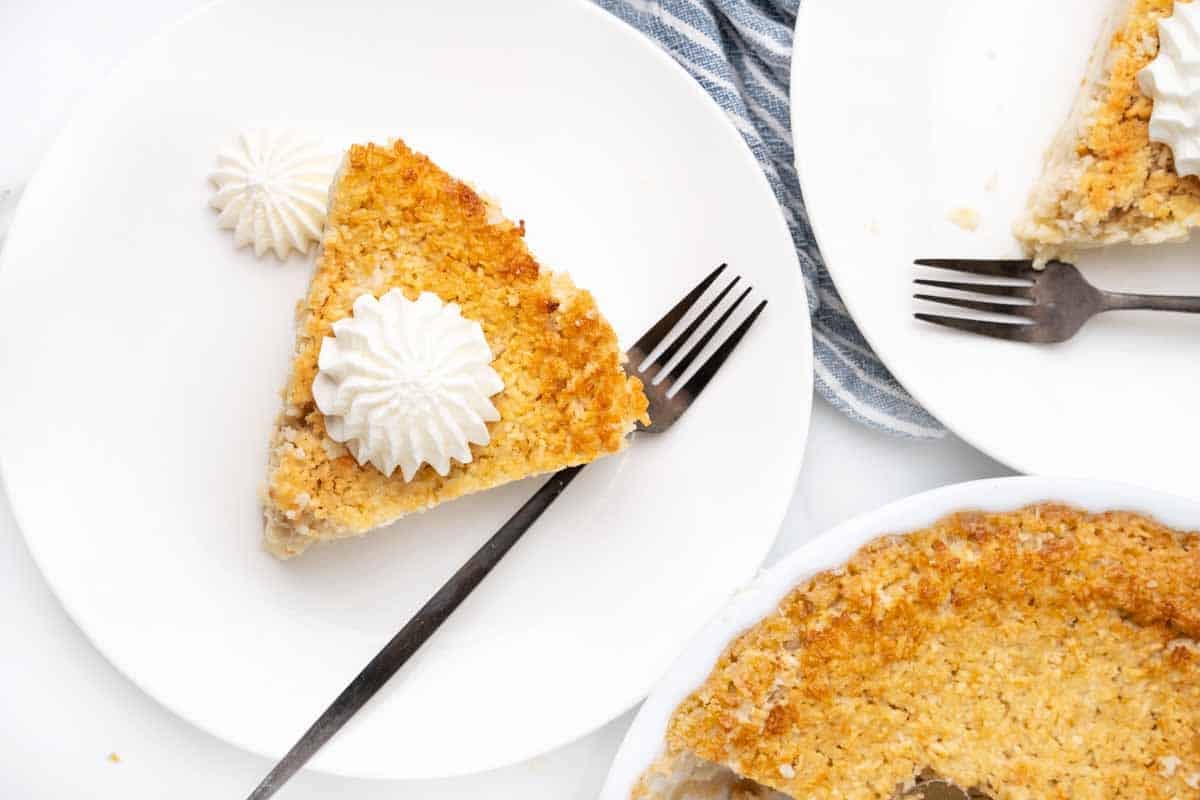 Slice of impossible pie with whipped cream on a white plate.