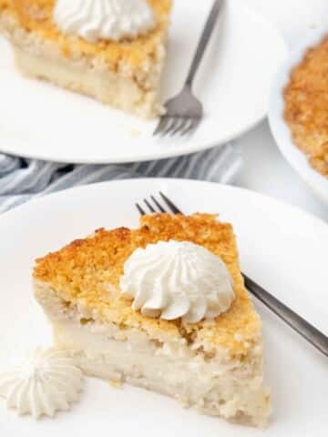 Slice of impossible pie with whipped cream on a white plate.