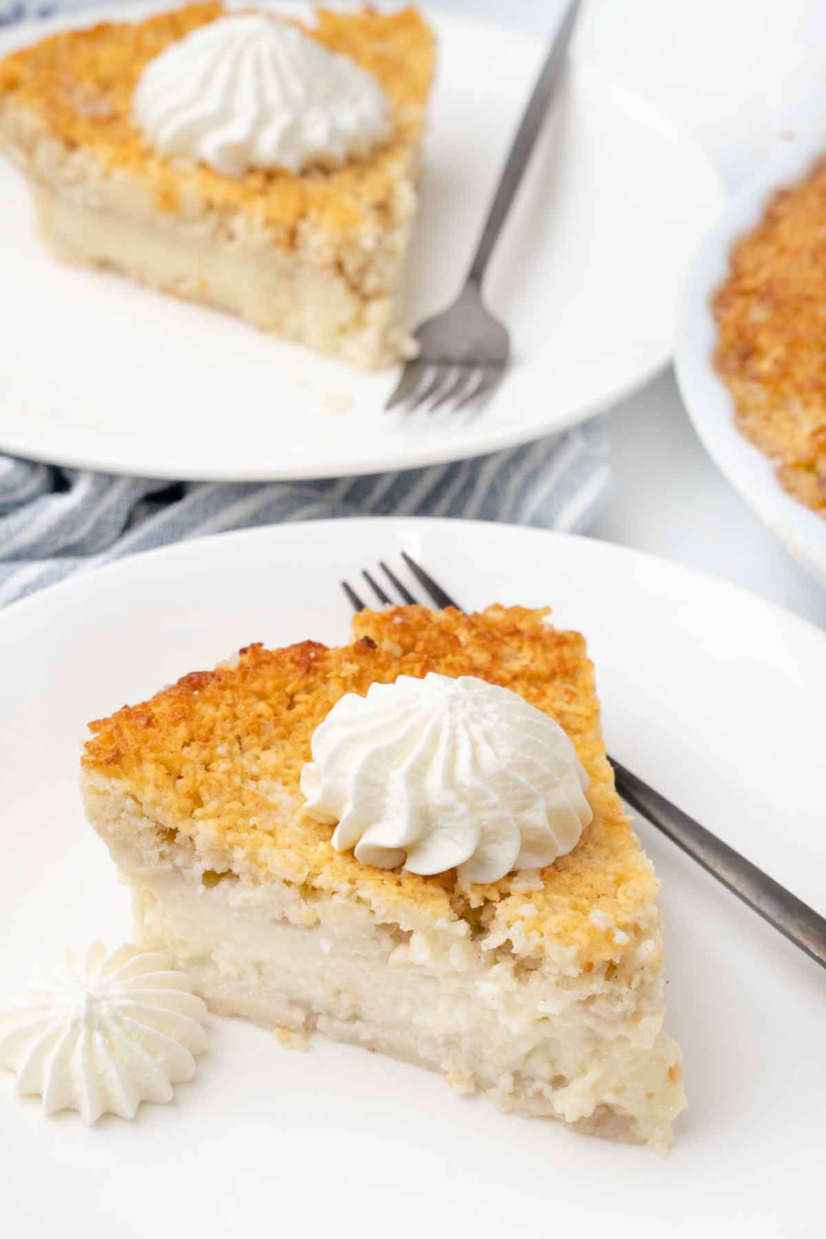 Slice of impossible pie with whipped cream on a white plate.