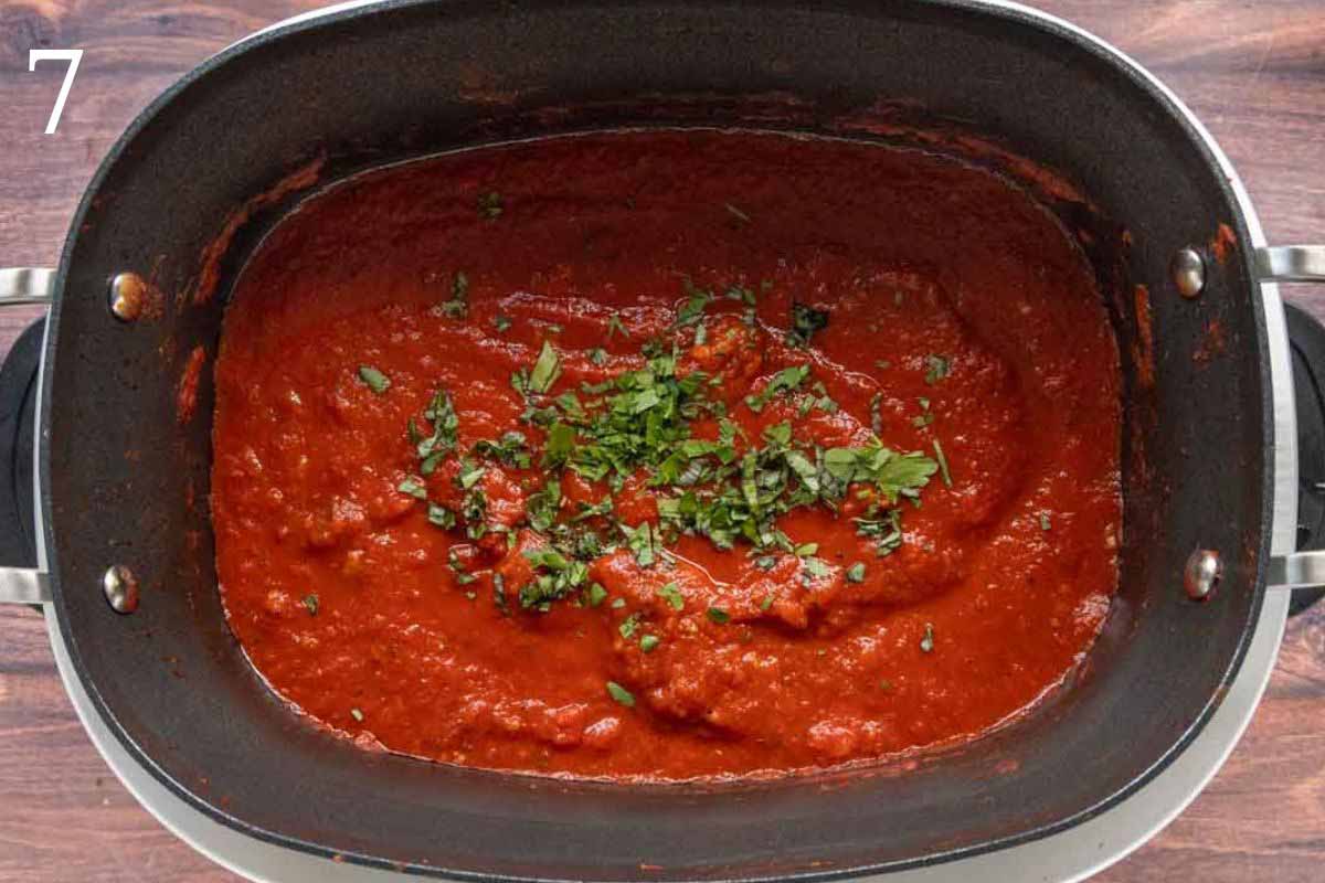 slow cooker spaghetti sauce in the slow cooker with a sprinkle of chopped basil.