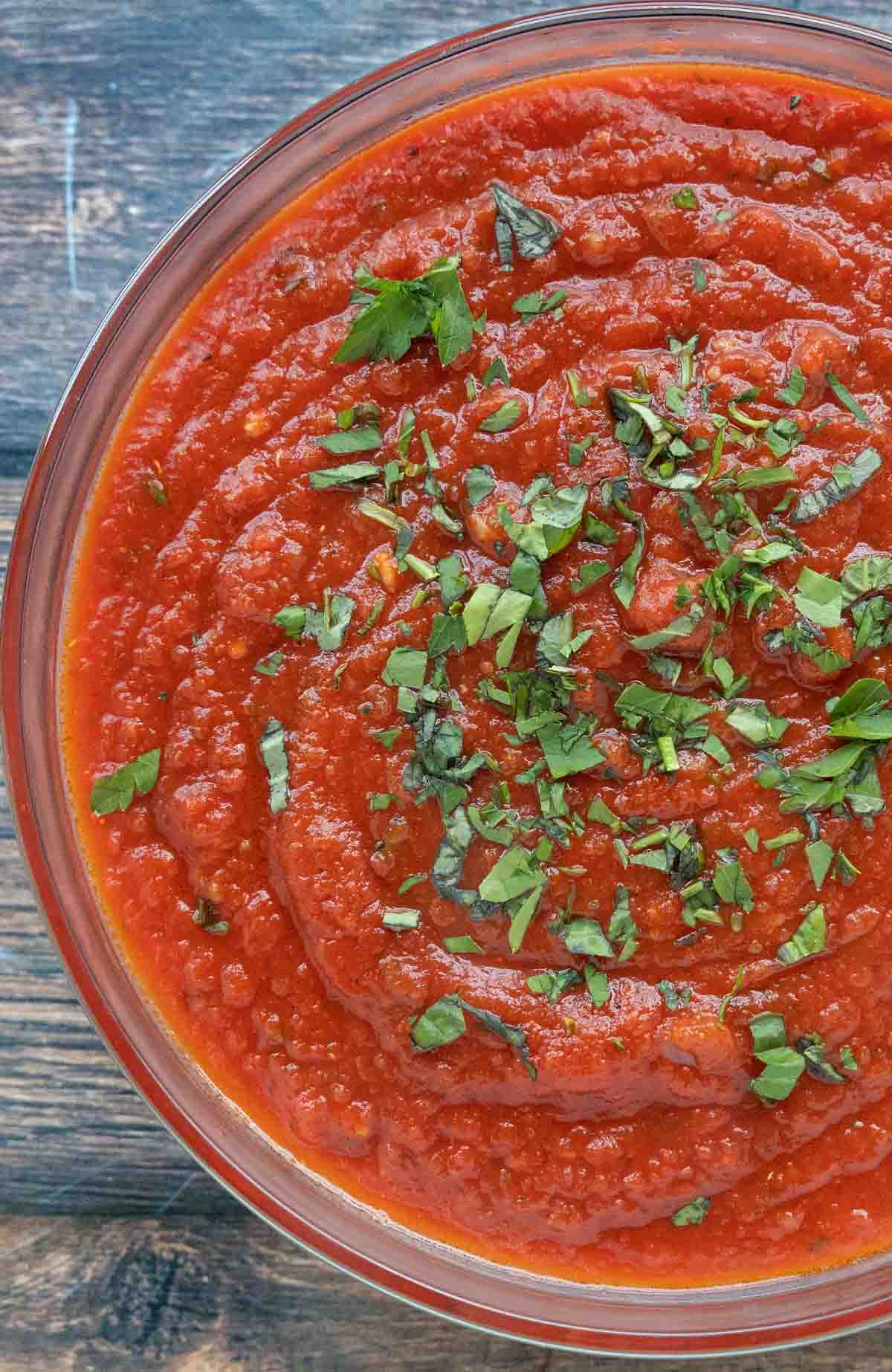 slow cooker spaghetti sauce in a bowl with a sprinkle of chopped basil.