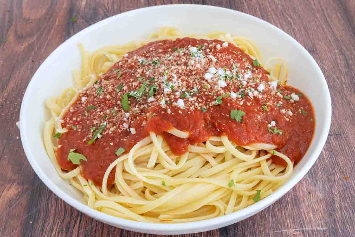 pasta topped with sauce slow cooker spaghetti sauce in a white bowl.
