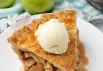 Slice of apple pie with vanilla ice cream on a white plate.