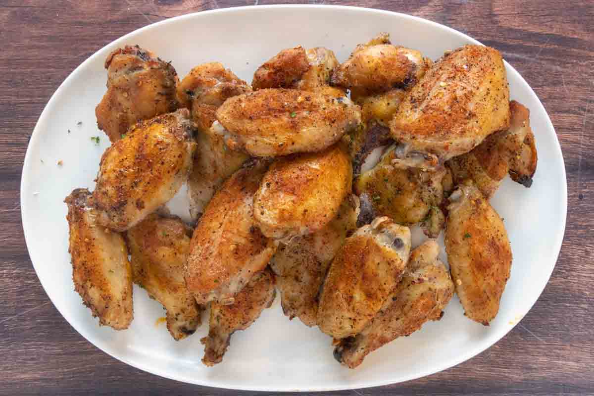 Crispy chicken wings on a white platter.