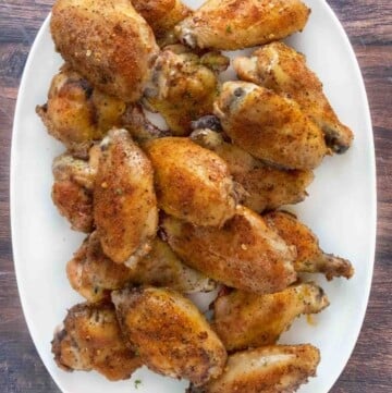 Crispy chicken wings on a white platter.