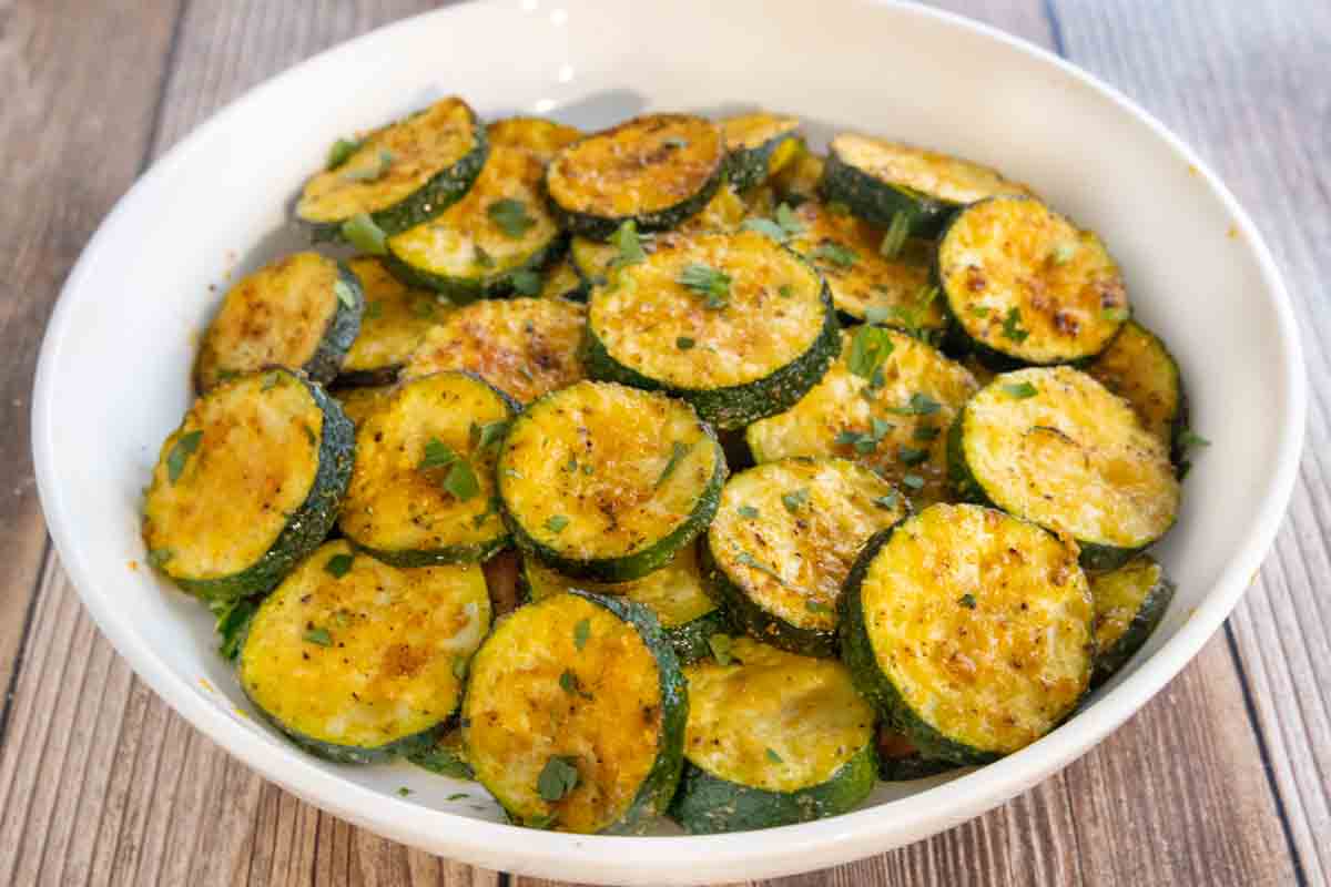 Oven roasted zucchini in a white bowl.