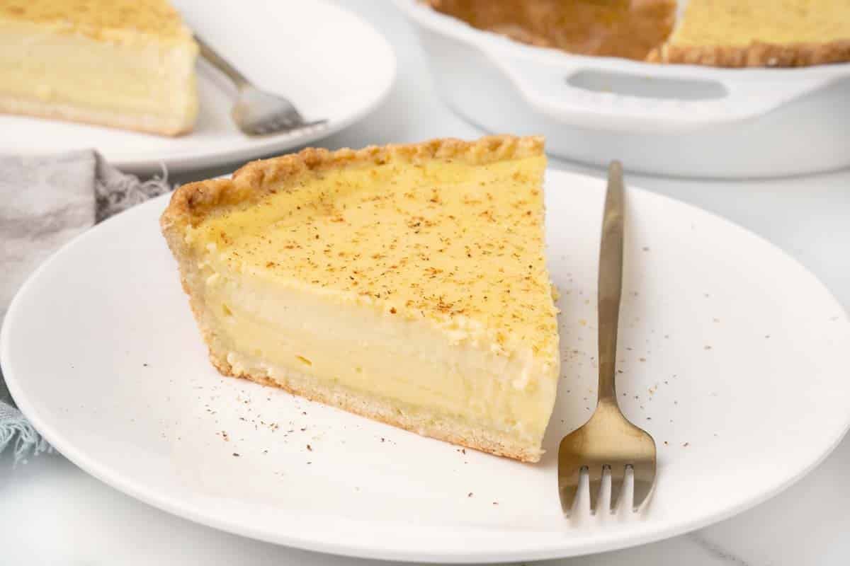 Slice of egg custard pie on a white plate with a fork.