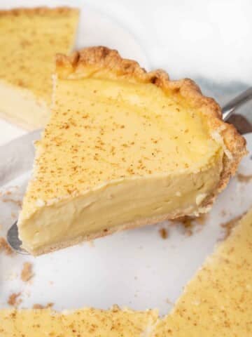 Slice of egg custard pie coming out of whole pie.