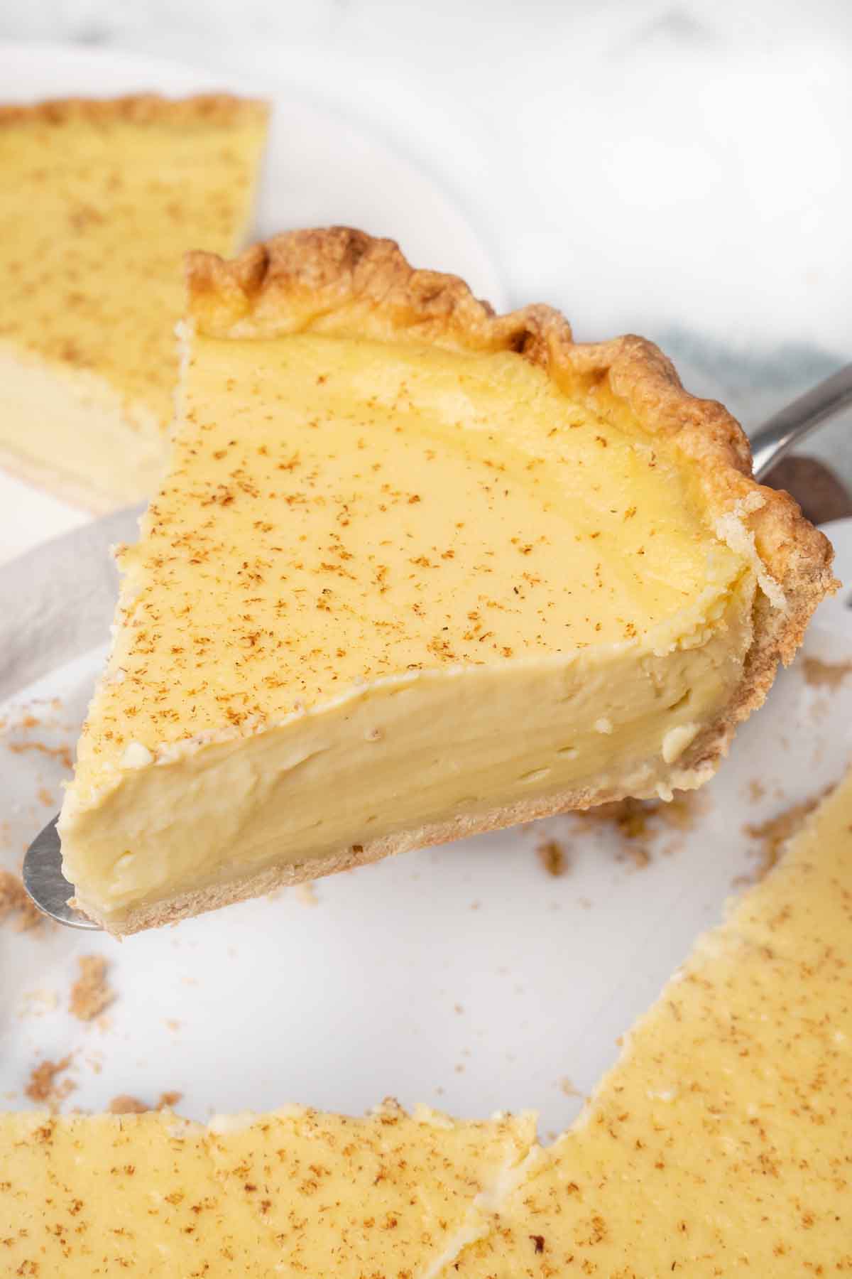 Slice of egg custard pie coming out of whole pie.
