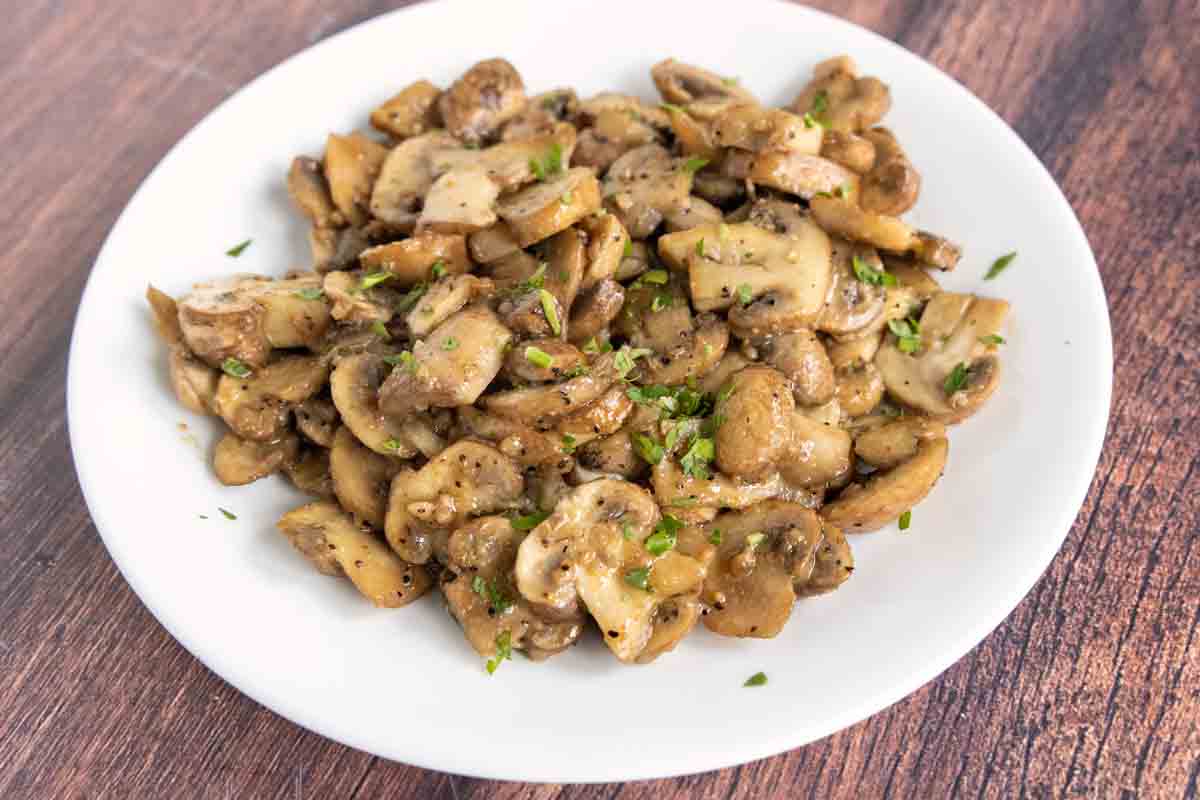 Sauteed mushrooms with garlic butter in a white bowl.