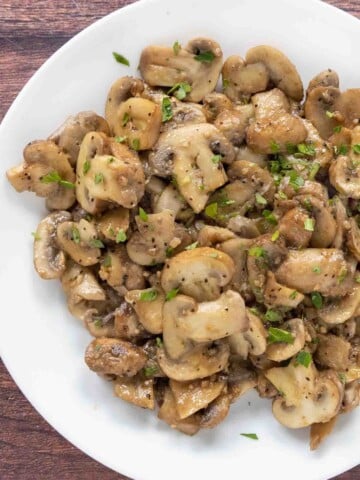 Garlic butter mushrooms in a white bowl.