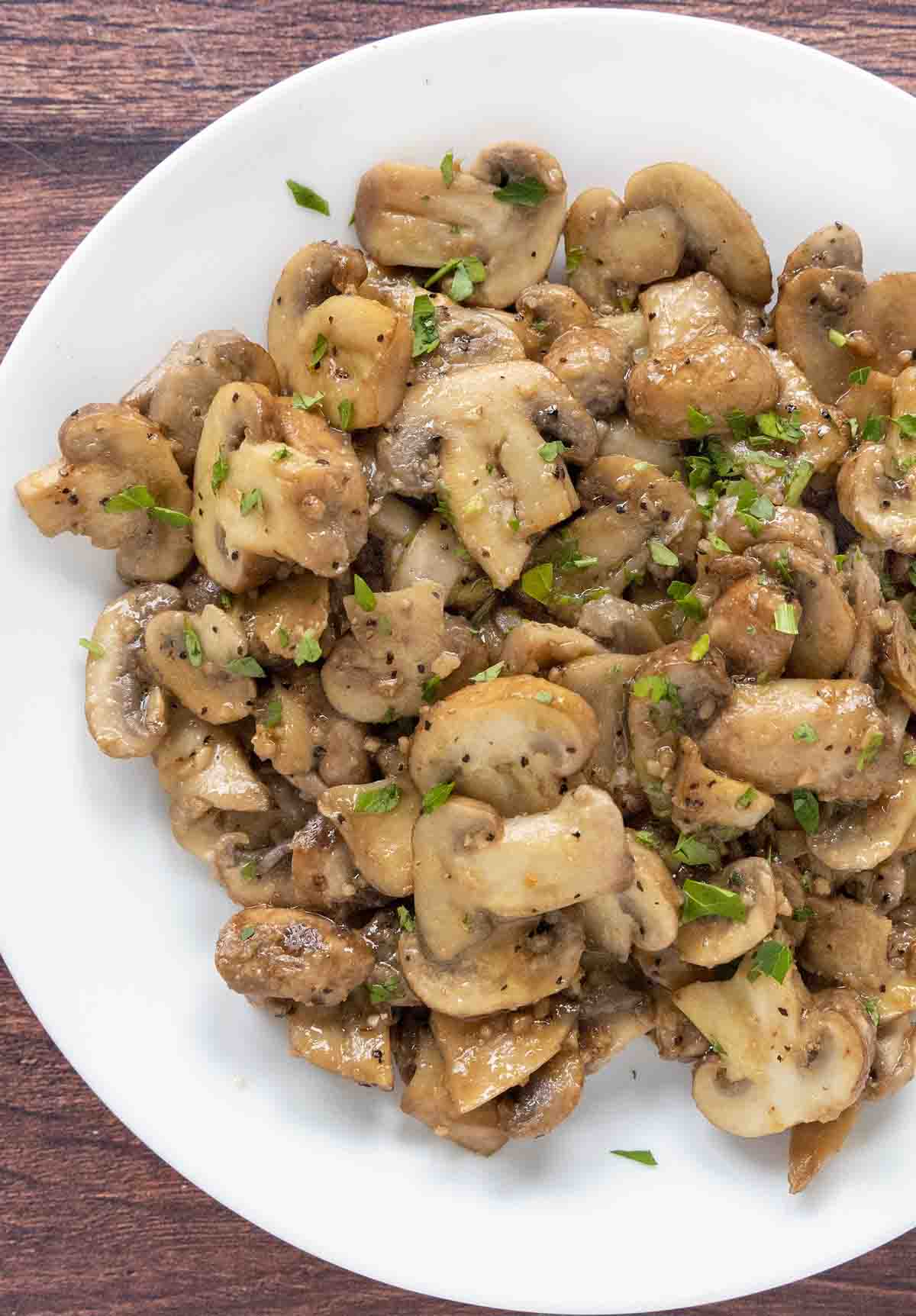 Sauteed mushrooms with garlic butter in a white bowl.