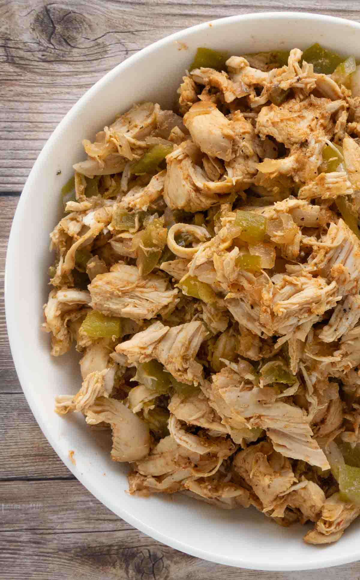 slow cooker shredded chicken in a white bowl.