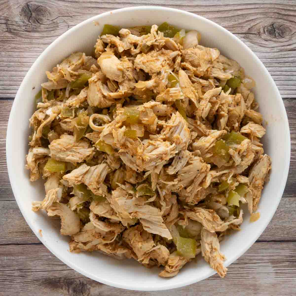 slow cooker shredded chicken in a white bowl.