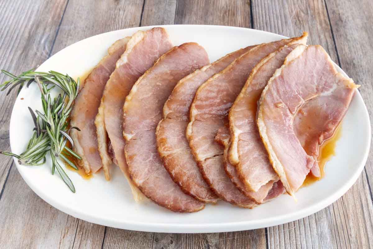 slow cooker spiral ham slices with pineapple slices on a white platter.
