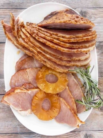 slow cooker ham slices with pineapple slices on a white platter.