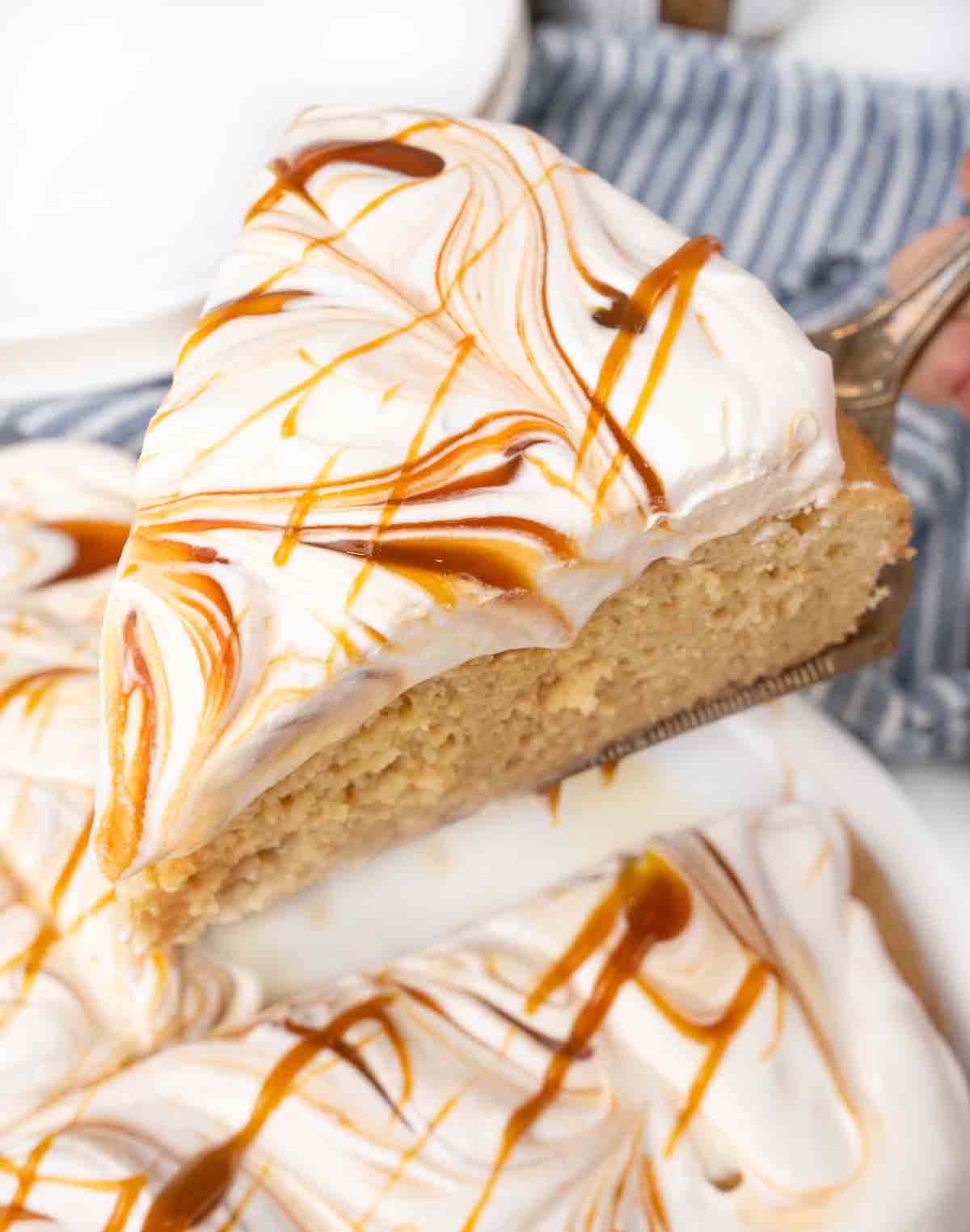 Slice of tres leches cake being taken out of whole cake.