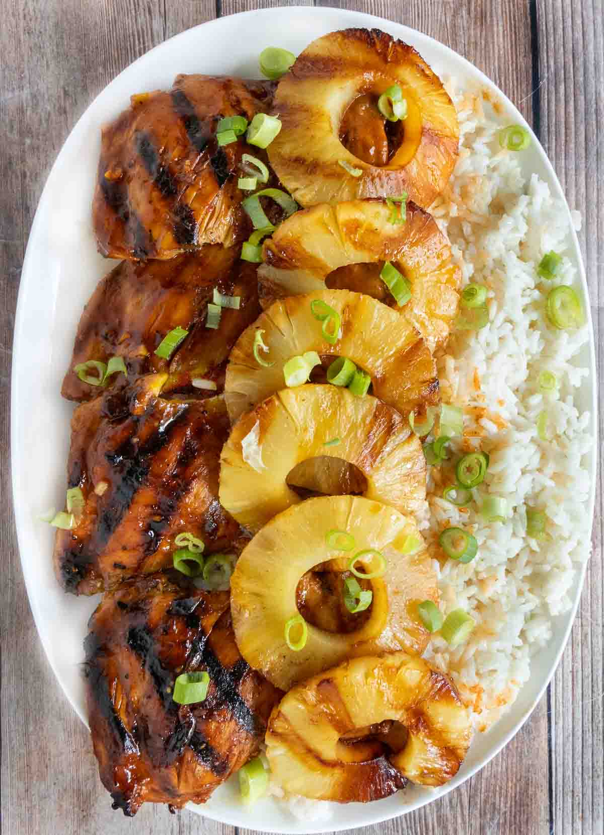 Huli Huli chicken with pineapple and rice on white platter.