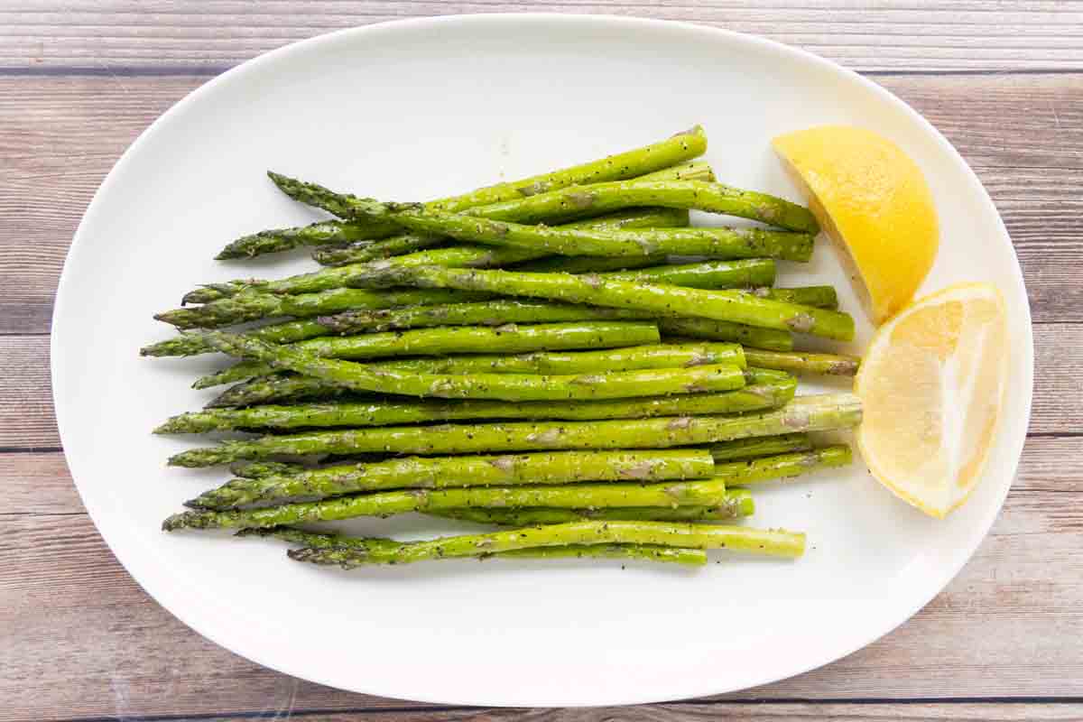 Roasted asparagus spears on a white platter.