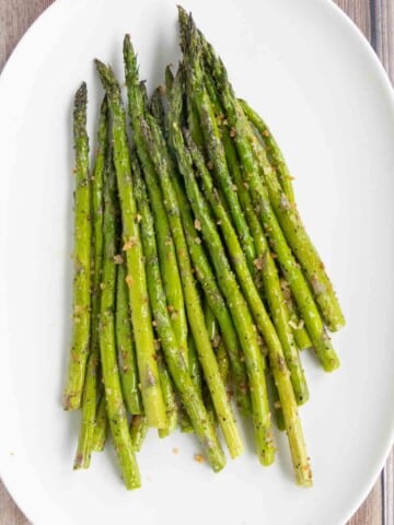 Roasted asparagus spears on a white platter.