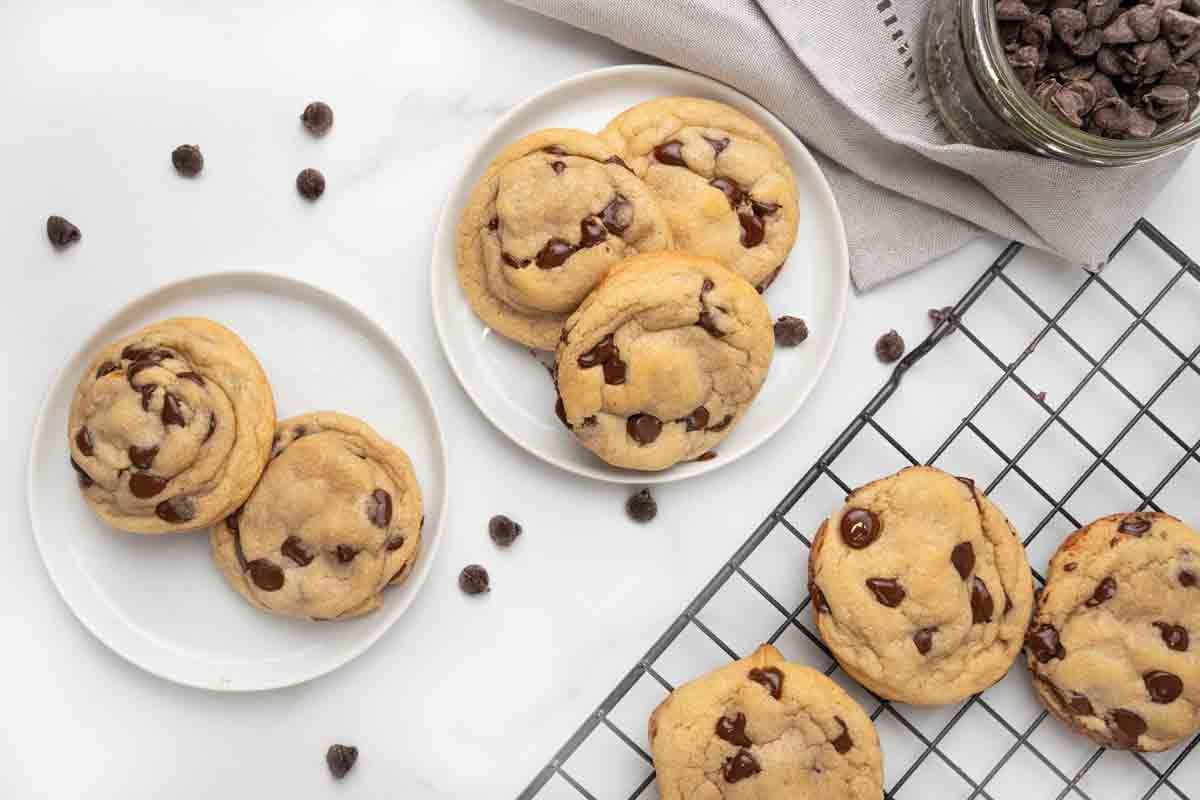 chocolate chip cookies on white plates next to wire rack with cookies.