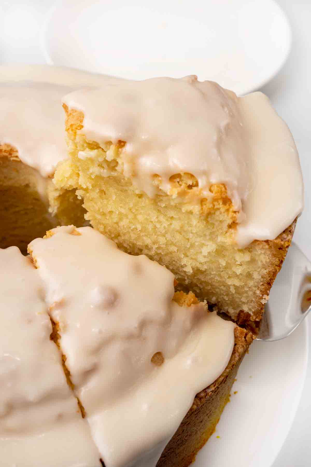 Slice of million dollar pound cake being taken out of the whole cake.