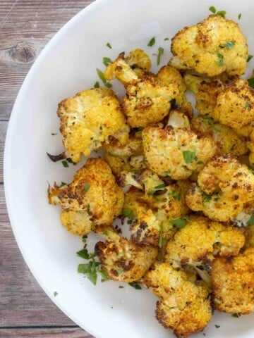 Oven roasted cauliflower in a white bowl.