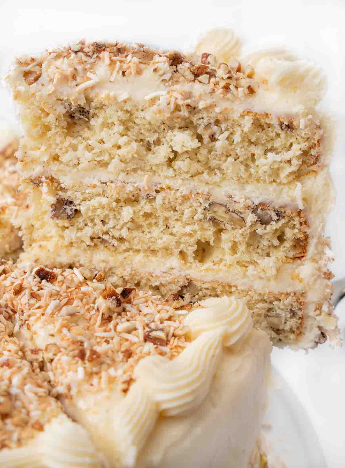 Slice of Italian cream cake being taking out of the whole cake.