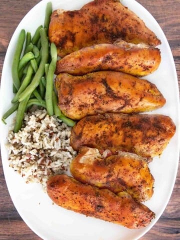Smoked chicken breasts on a white platter.