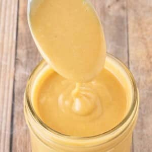 Chick-fil-A sauce in glass jar with a spoon of sauce coming out.