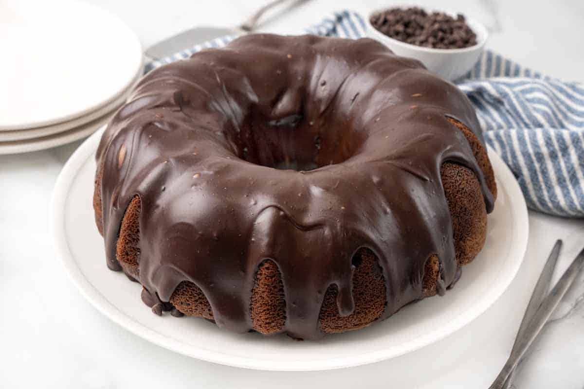 Whole chocolate bundt cake on a white platter.