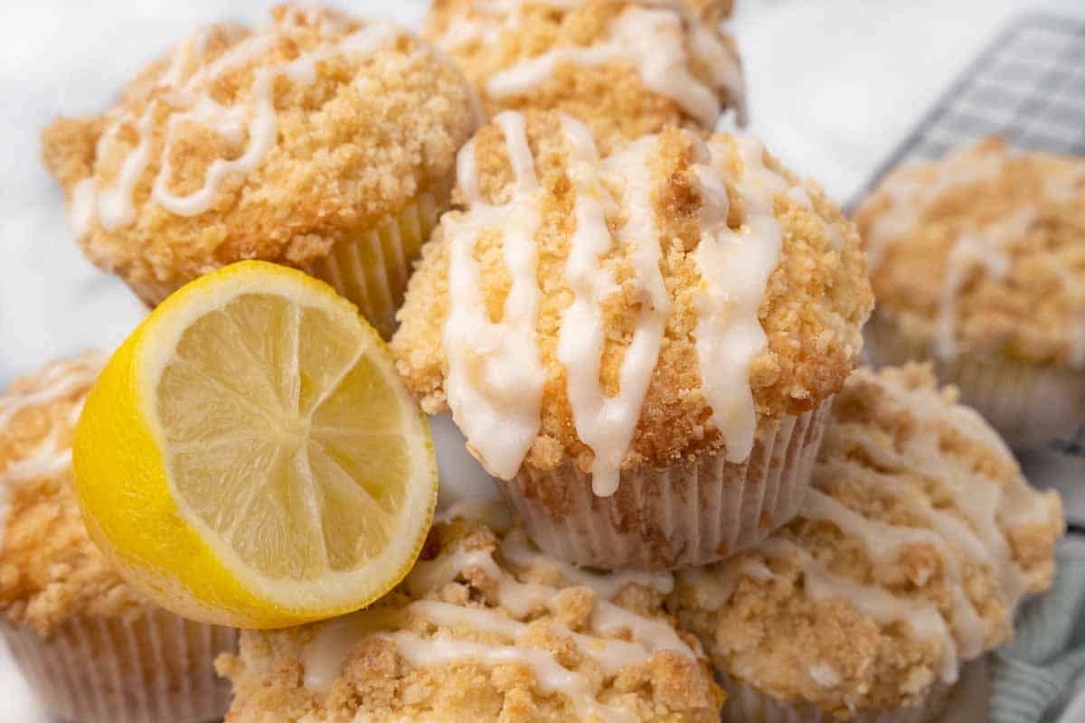 Lemon streusel muffins with half a lemon on white platter.