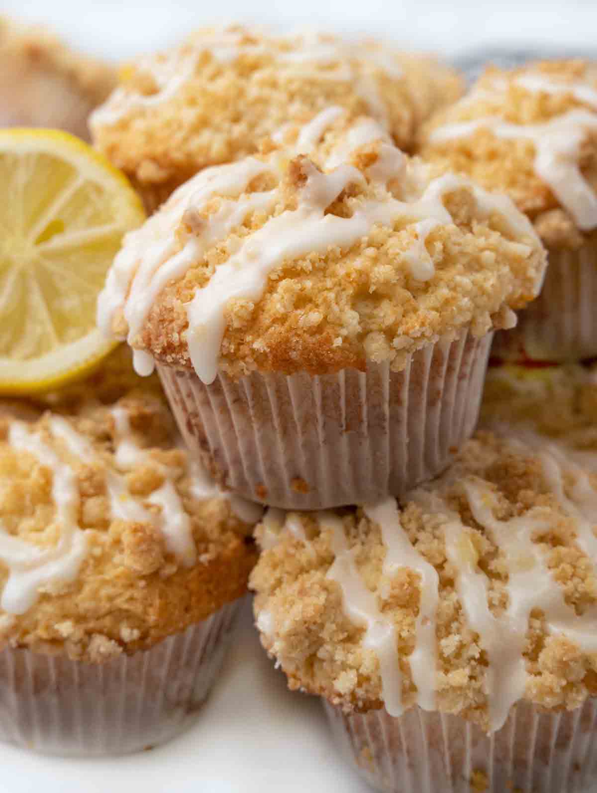 Lemon streusel muffins with half a lemon on white platter.