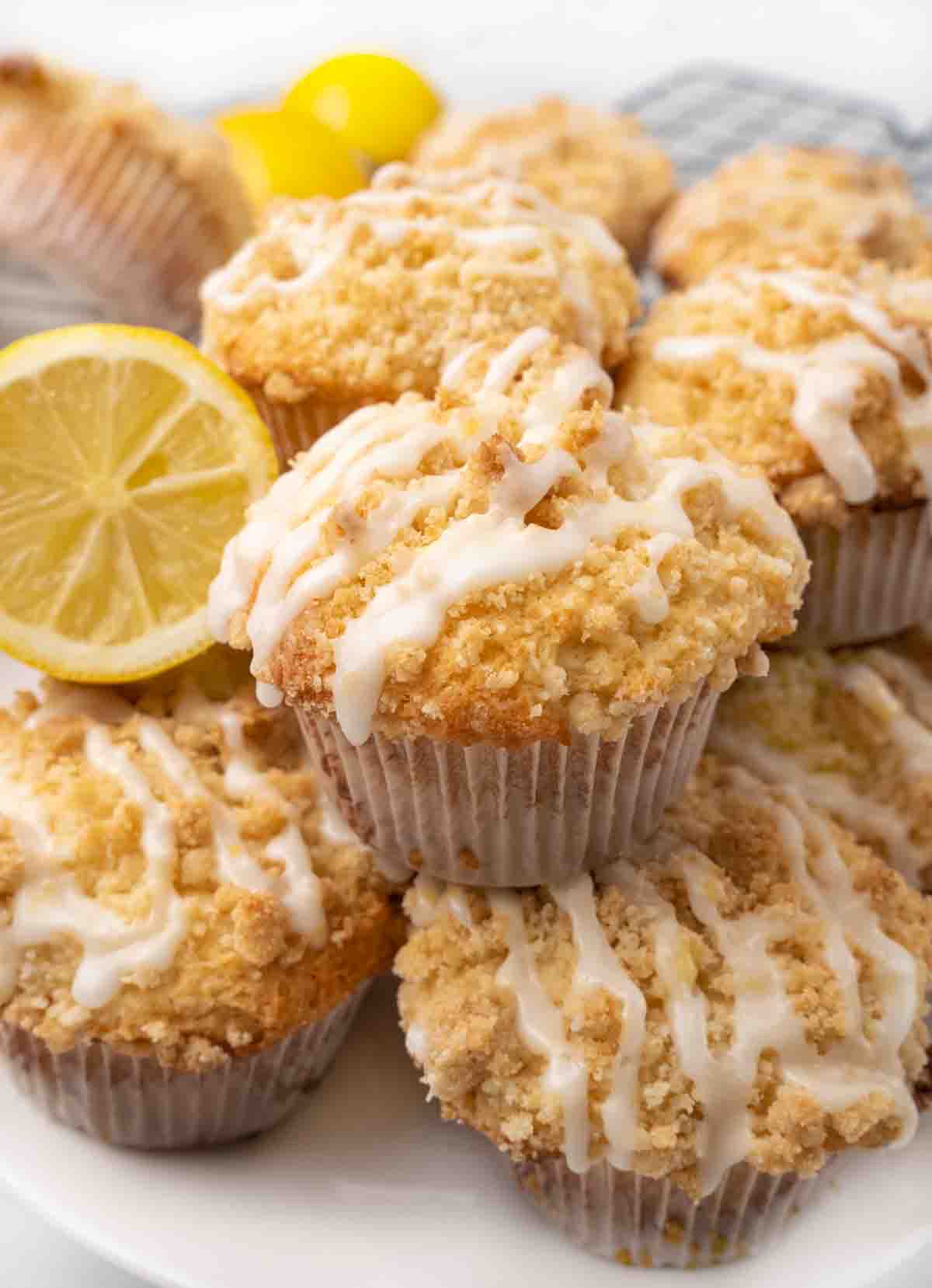 Lemon streusel muffins with half a lemon on white platter.