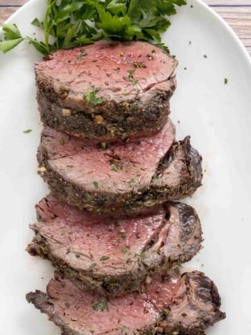 Sliced roasted beef tenderloin on a white platter